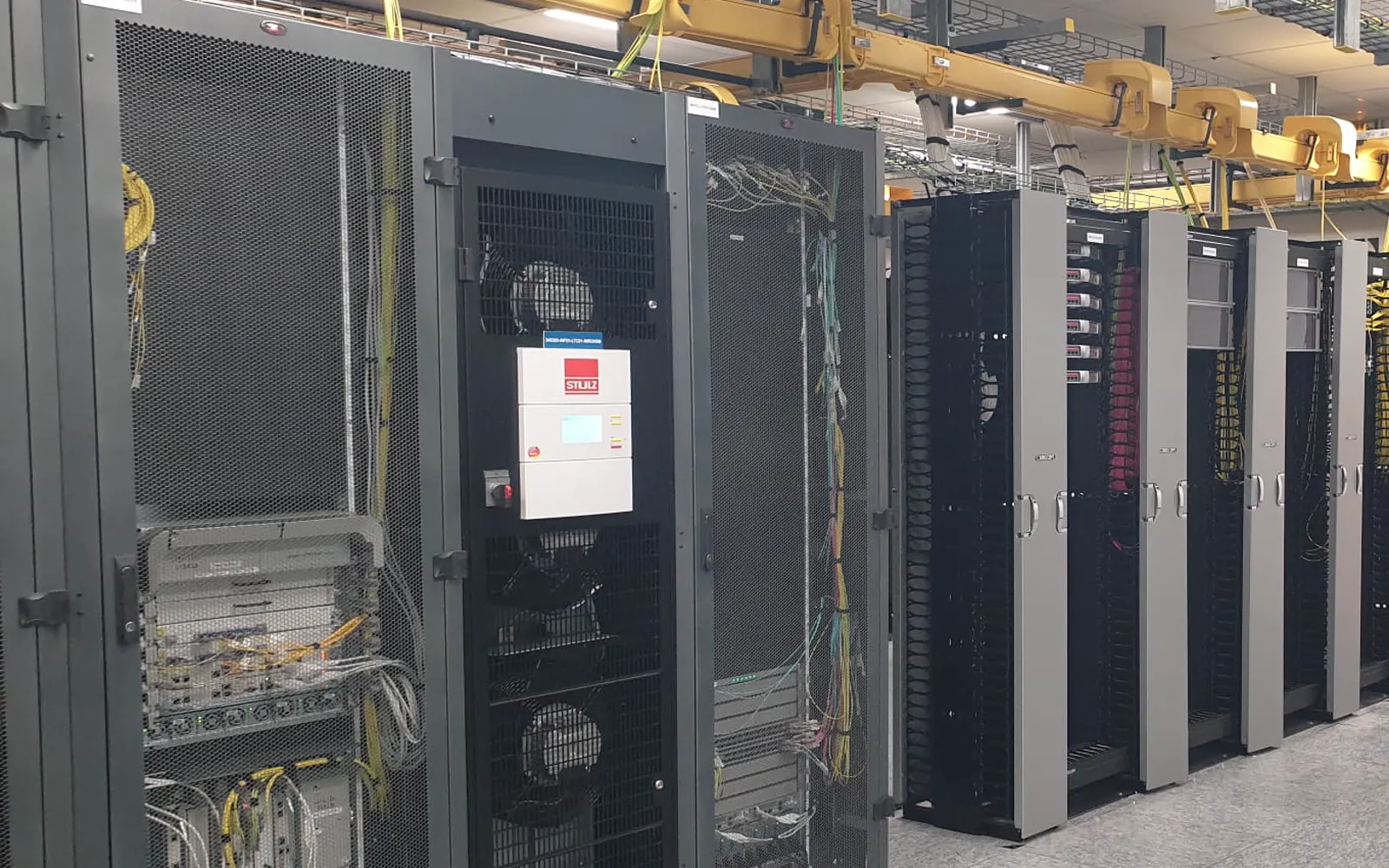 Salle informatique&nbsp;: baies, armoire de climatisation et chemins de câbles fibre jaunes au plafond